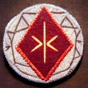 "The Kamirakurai patch features a deep blood red lightning bolt striking down at a hexagonal block, which pays homage to their spiritual ancestors of the Rangers.  Ringing the emblem, the words 'KAMIRAKURAI' stands atop the emblem, and the words 'WITH SHOCK AND BLOOD' sit at the bottom."